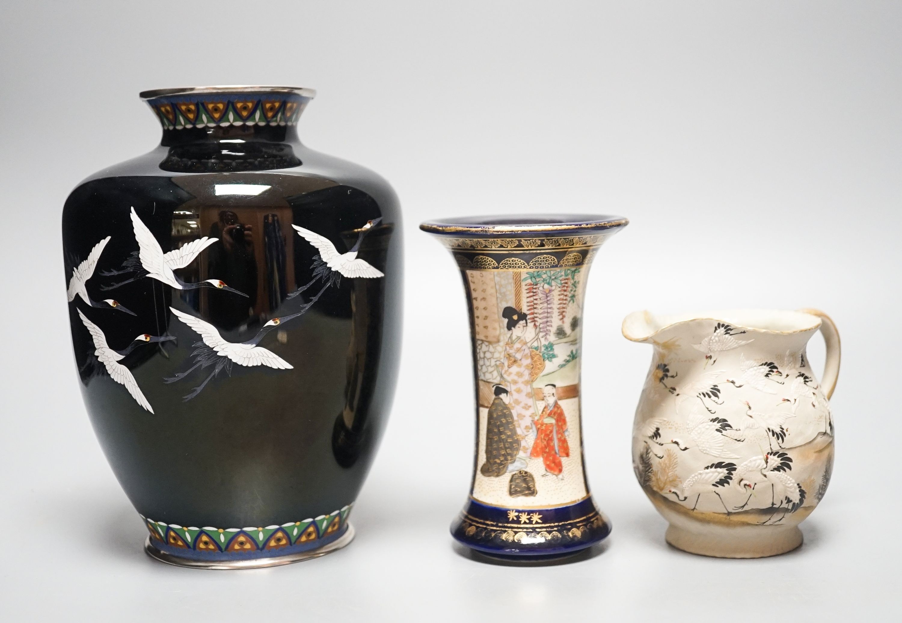 A Japanese black ground ‘cranes’ cloisonné enamel vase, 18.3cm, a Satsuma pottery vase and a crane decorated jug (3)